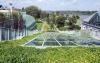 Park with trees, lawn and a pitched green roof with stairs